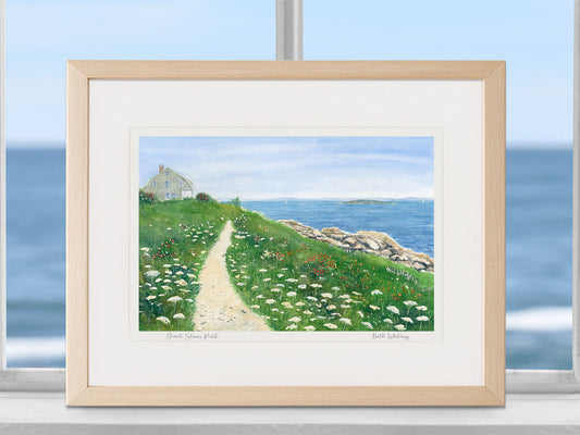 Framed watercolor print of Giant Stairs Path, Harpswell, Maine, in a warm wood frame in a coastal window setting.