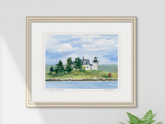 Framed watercolor print of Pumpkin Island Light, Little Deer Isle, Maine, in a light gold frame on a sunny wall with a fern.