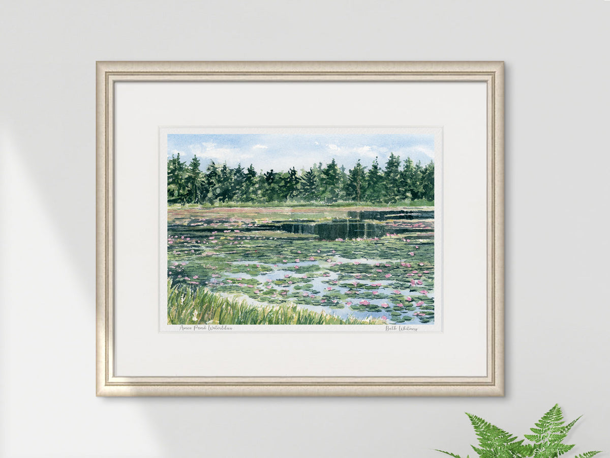 Framed watercolor print of Ames Pond waterlilies, Stonington, Maine, in a silver frame on a neutral wall.