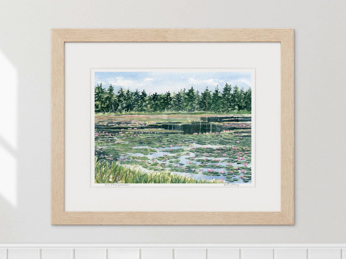 Framed watercolor print of Ames Pond waterlilies, Stonington, Maine, in a warm wood frame.