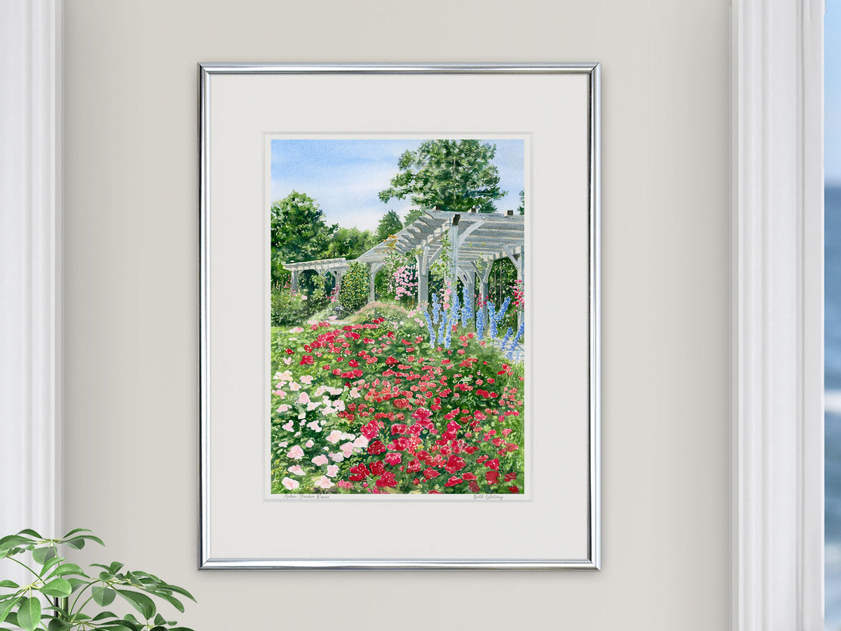 Framed watercolor print of the Arbor Garden roses and pergola at Coastal Maine Botanical Gardens, displayed in a coastal living room.