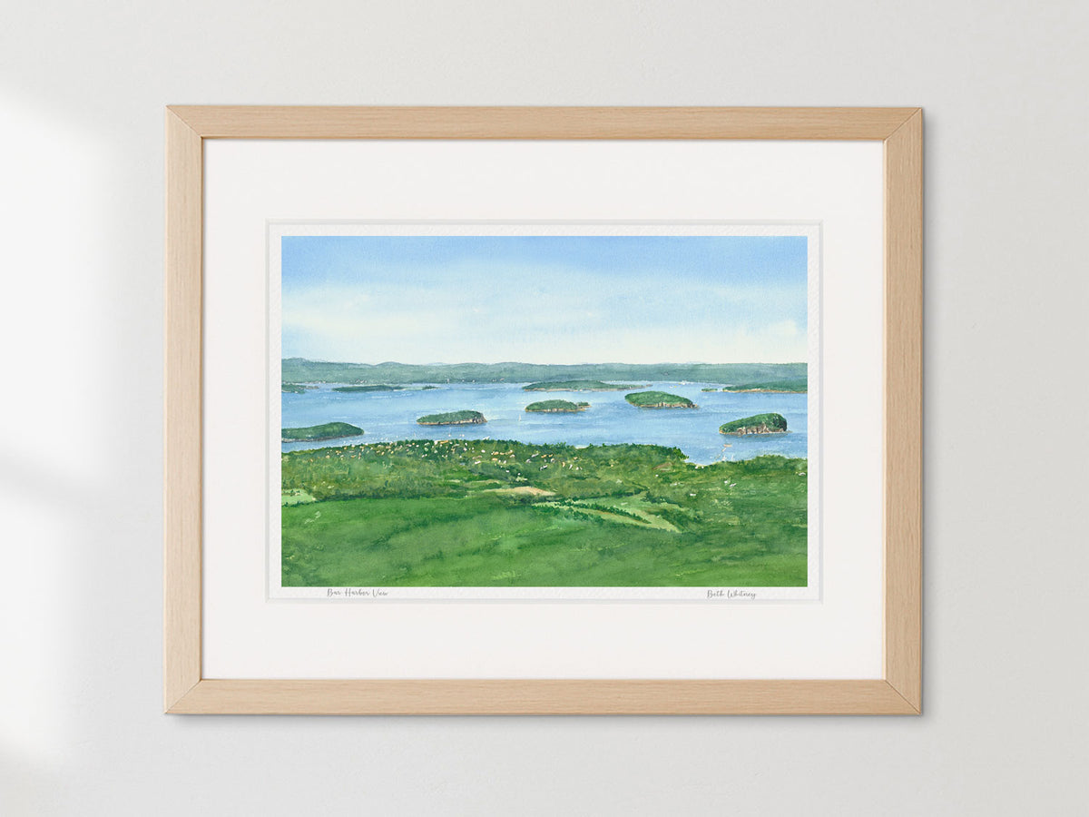 Framed watercolor print of Bar Harbor View from Cadillac Mountain in a neutral warm frame on a white wall.