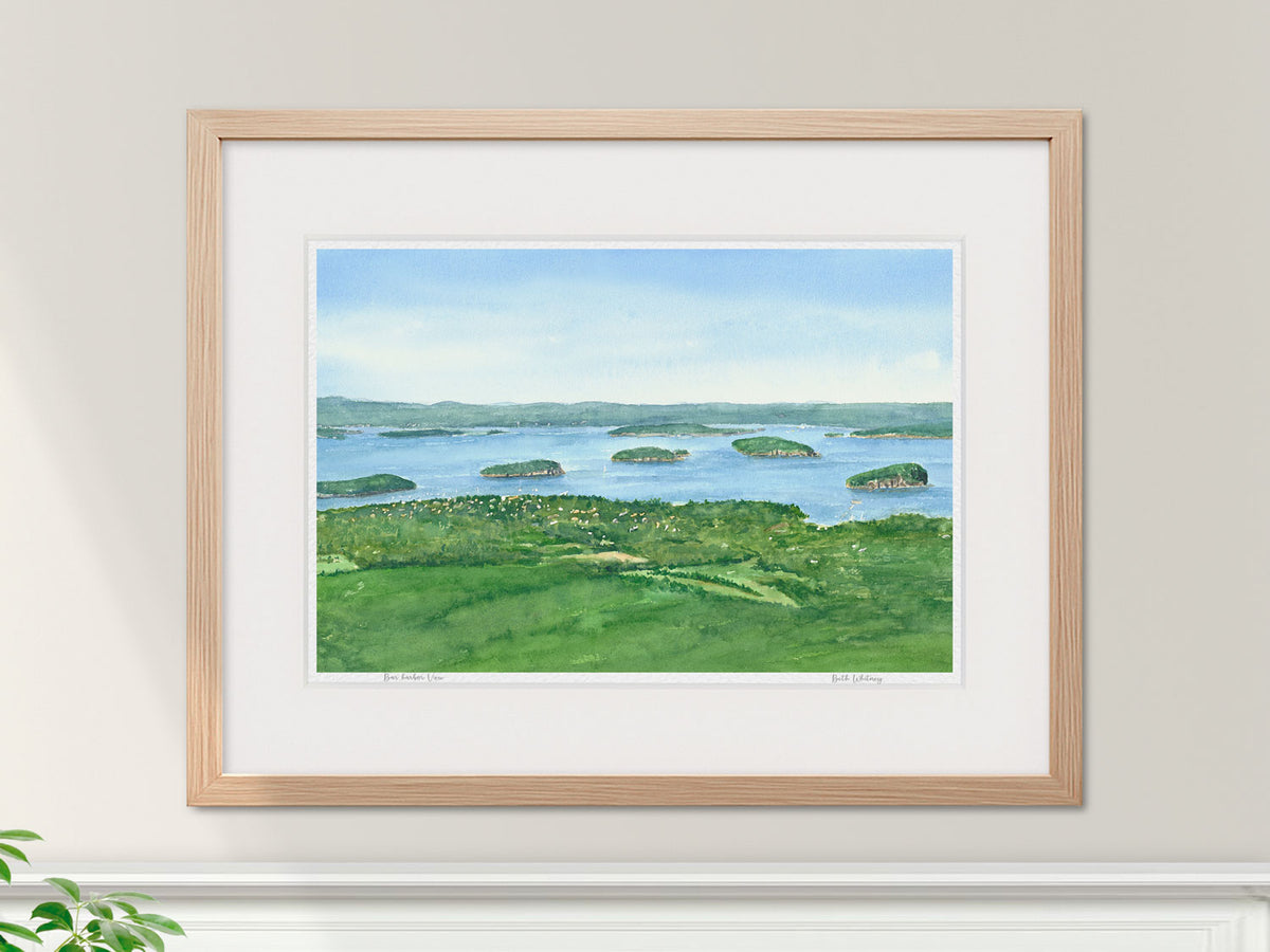 Framed watercolor print of Bar Harbor View, Acadia National Park, in a warm wood frame in an interior setting.