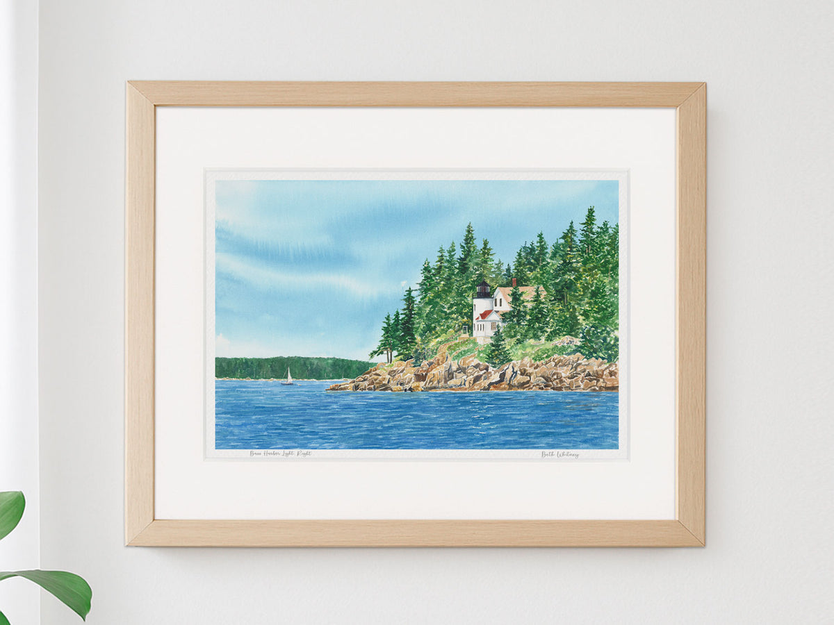 Framed watercolor print of Bass Harbor Light, Right, in a warm wood frame on a white wall.