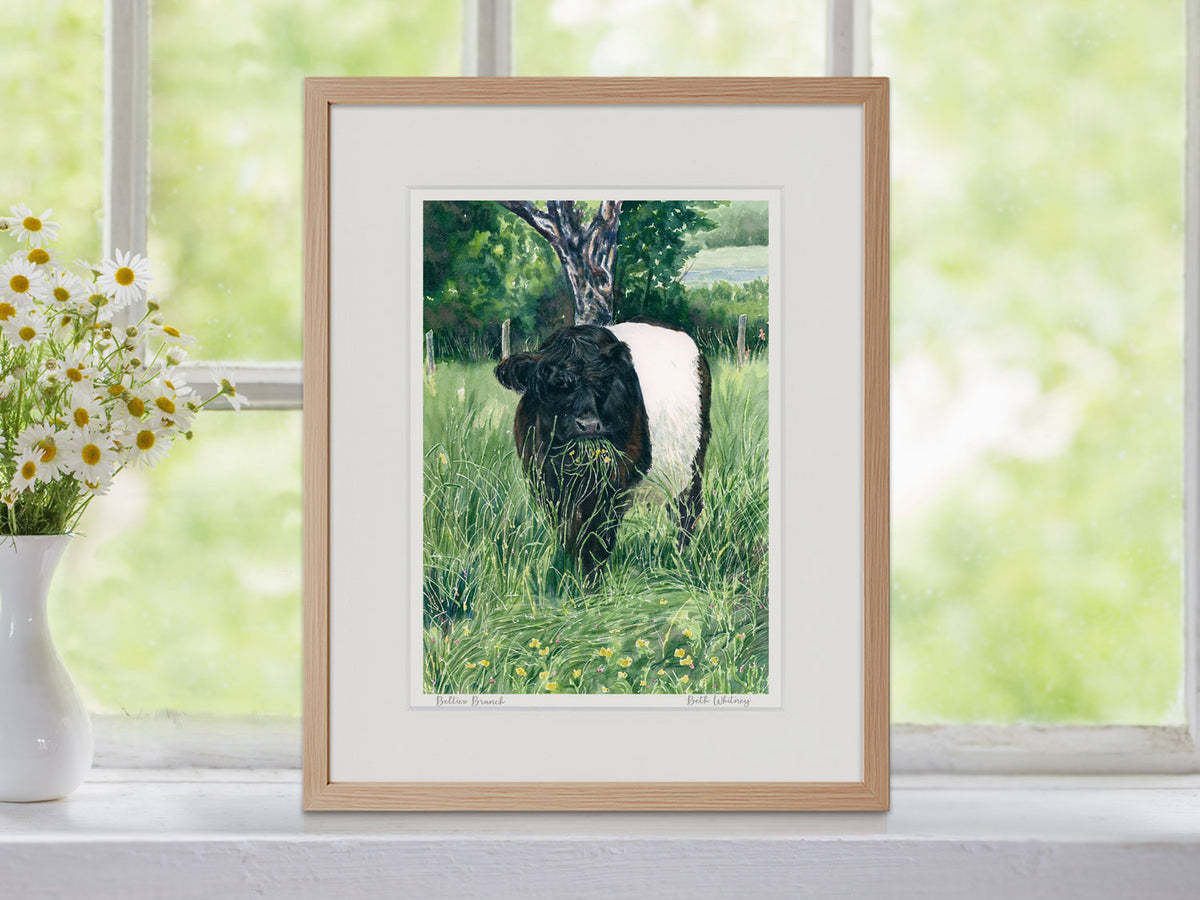 Framed watercolor print of Beltie's Brunch in a warm wood frame, styled with botanical greenery.