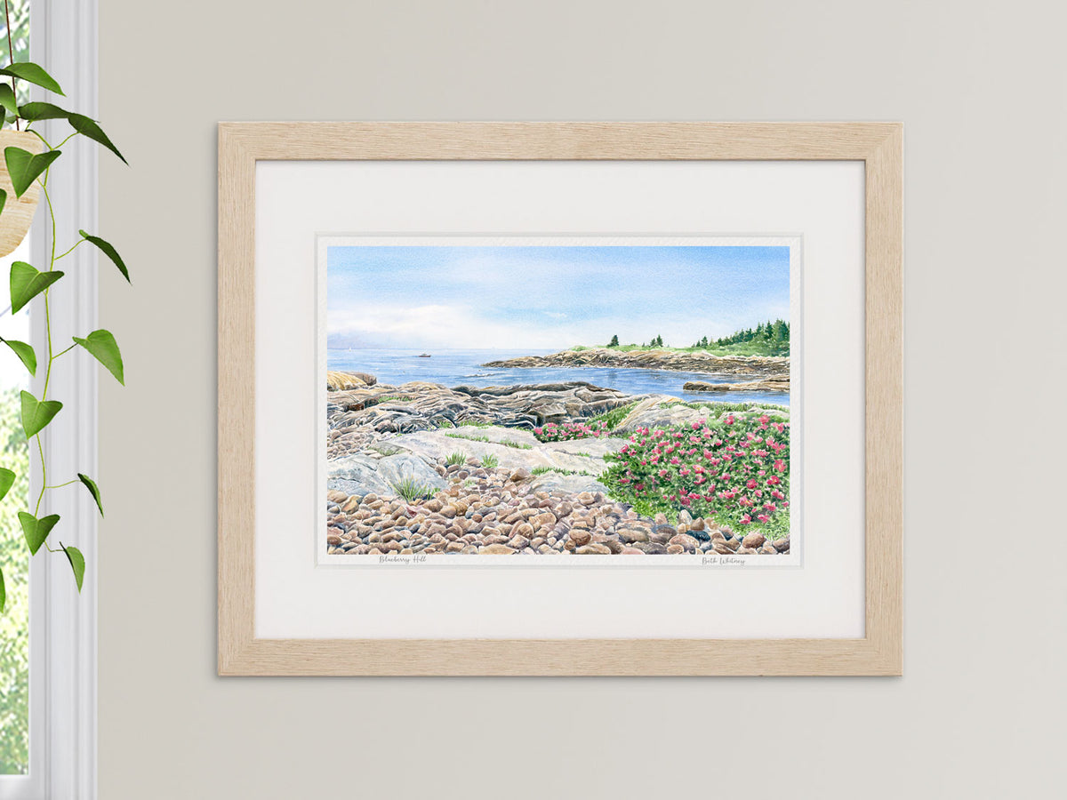 Framed watercolor print of Blueberry Hill, Schoodic Point, in a natural wood frame in an interior setting.