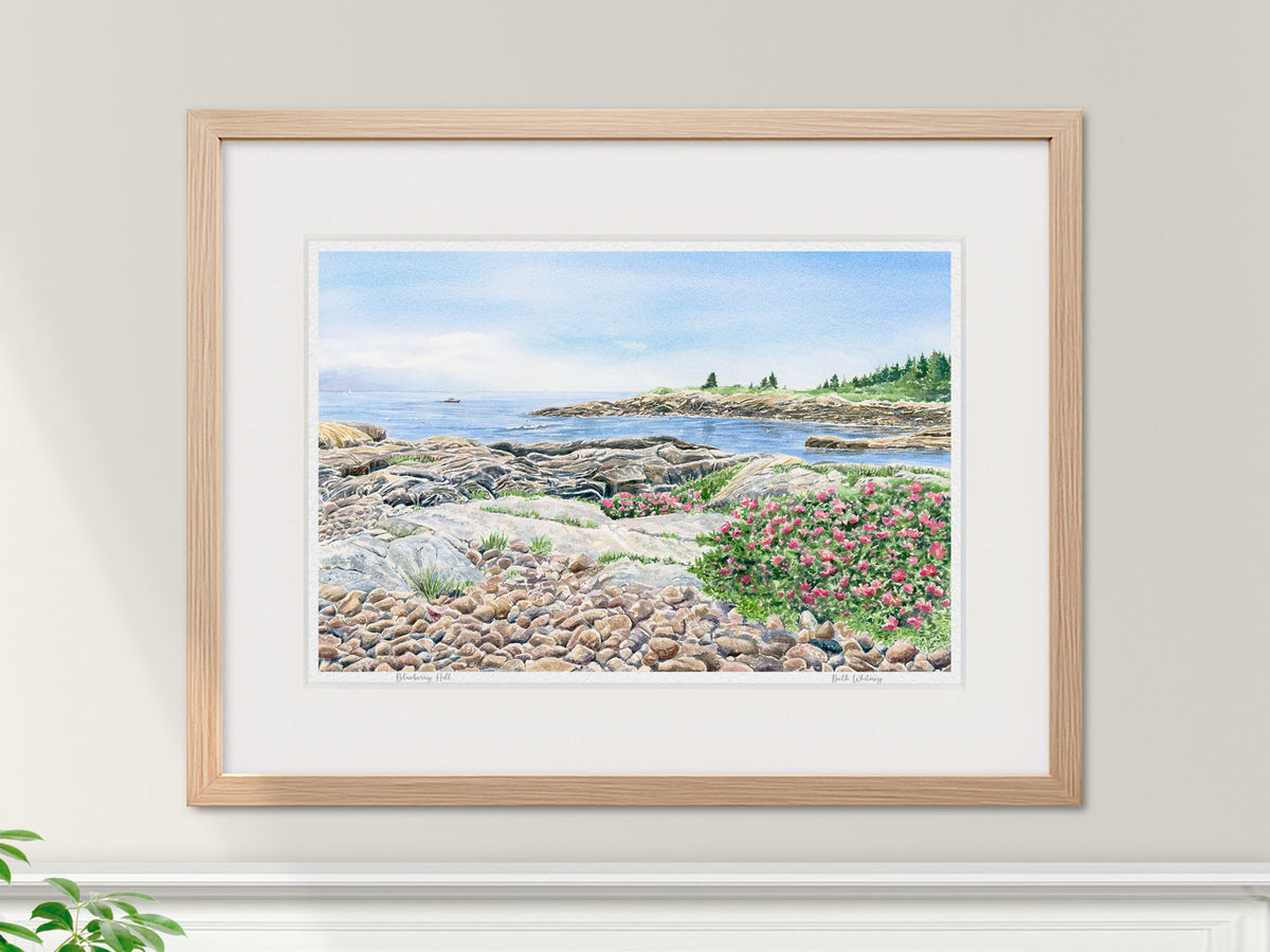 Framed watercolor print of Blueberry Hill, Schoodic Point, in a warm wood frame in an interior setting.