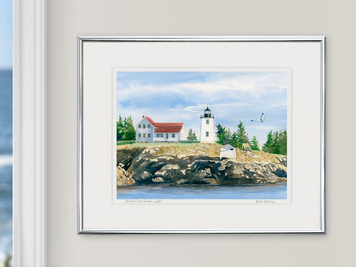 Framed watercolor print of Burnt Coat Harbor Light, Hockamock Head, in a silver frame on a neutral wall.