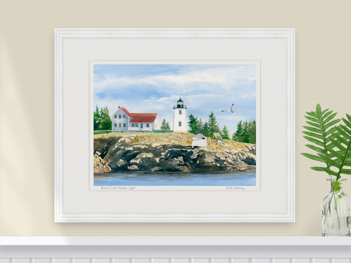 Framed watercolor print of Burnt Coat Harbor Light, Swans Island, Maine, in a warm wood frame with fern styling.