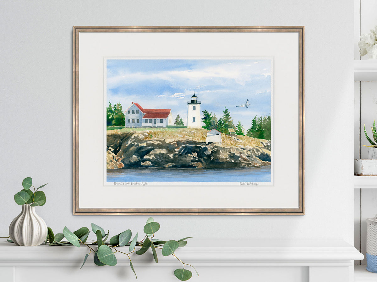 Framed watercolor print of Burnt Coat Harbor Light in a warm wood frame with botanical styling.