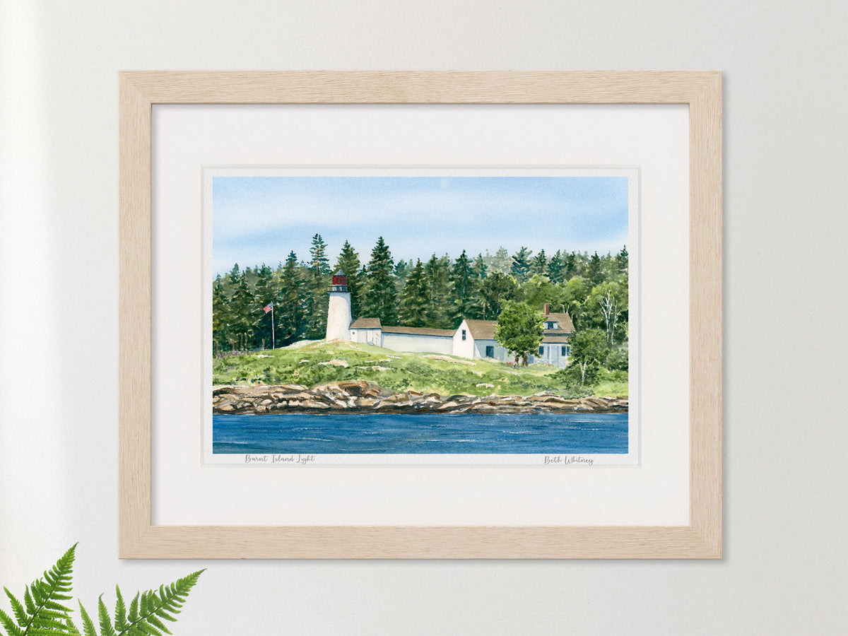 Framed watercolor print of Burnt Island Light, Boothbay Harbor, in a warm wood frame with fern styling.