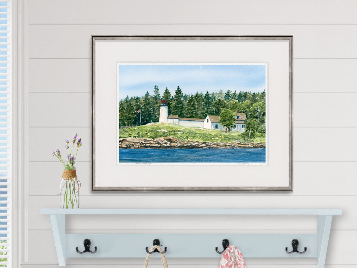 Framed watercolor print of Burnt Island Light in a pewter frame over a blue coat rack