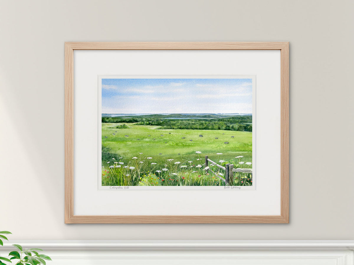 Framed watercolor print of Caterpillar Hill, Sedgwick, Maine, in a warm wood frame in a lifestyle setting.