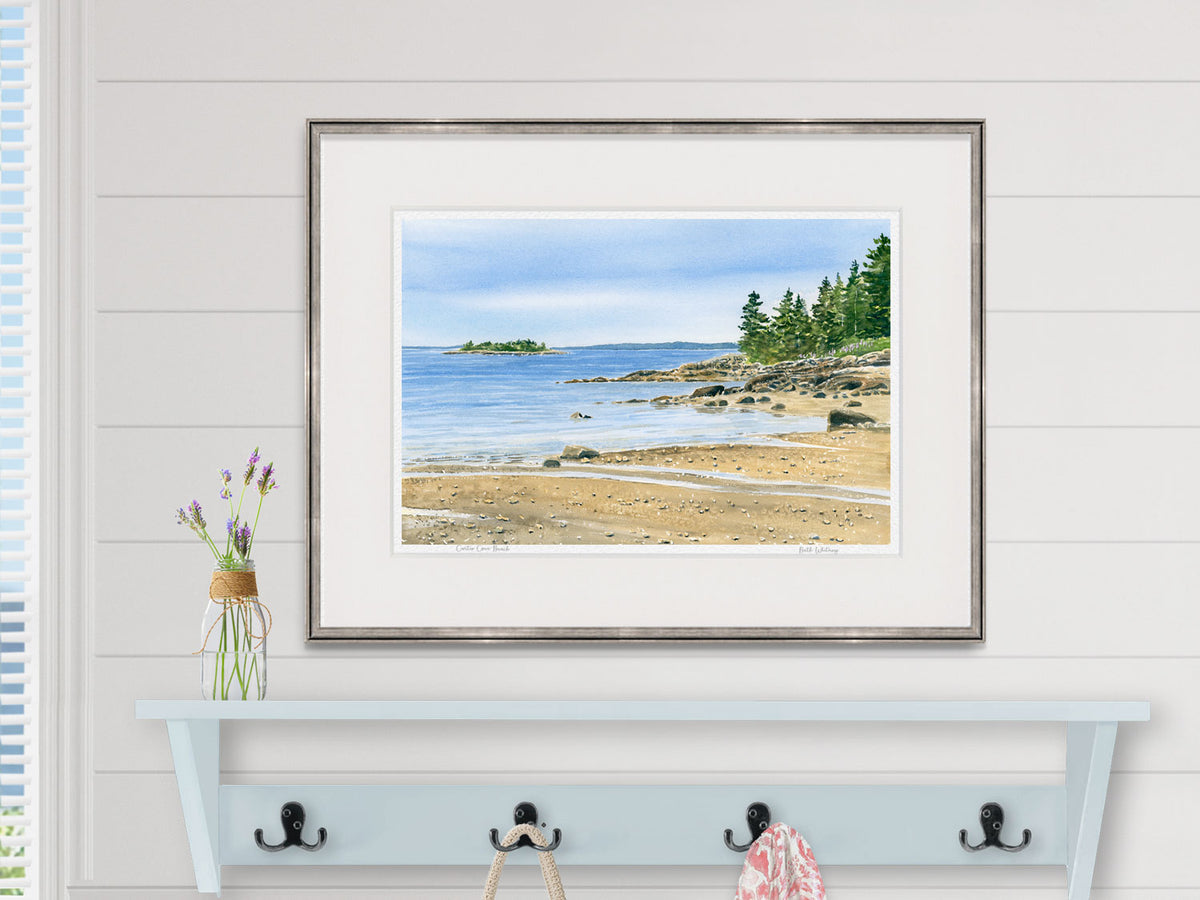 Framed watercolor print of Curtis Cove Beach, Blue Hill Peninsula, displayed above a bathroom shelf.