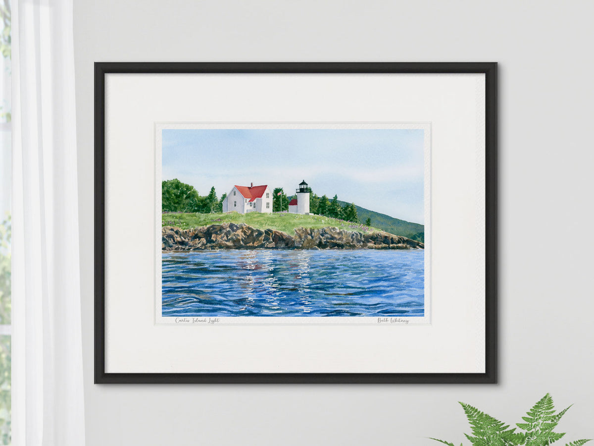 Framed watercolor print of Curtis Island Light, Camden Harbor, in a black frame on a neutral wall.