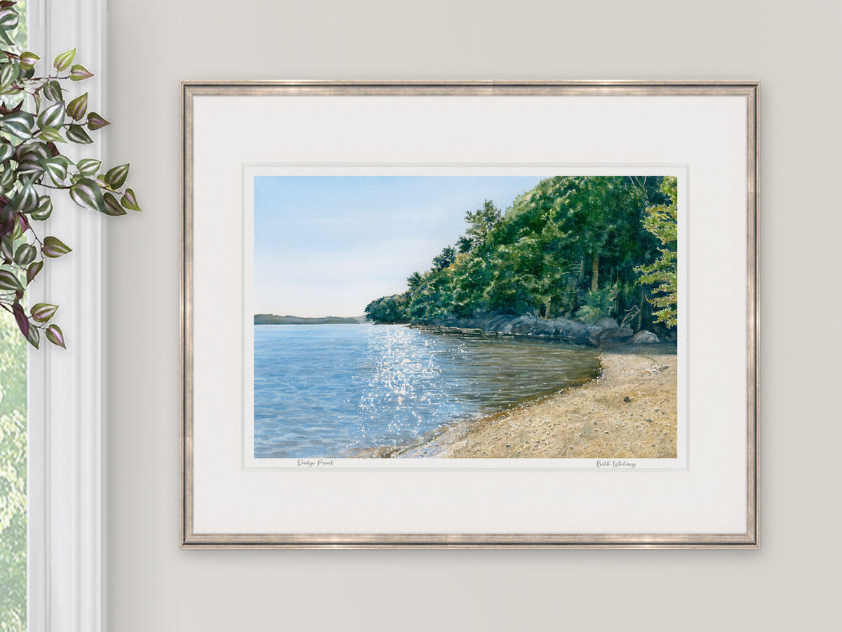 Framed watercolor print of Dodge Point Preserve, Newcastle, Maine, in a pale metal frame with natural window light.