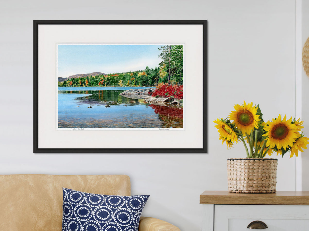 Framed watercolor print of Eagle Lake Fall in a black frame in a lifestyle setting with sunflowers.