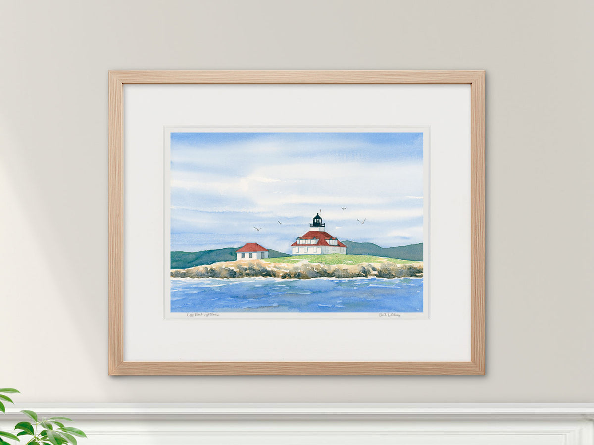 Framed watercolor print of Egg Rock Lighthouse in a warm wood frame with botanical styling.