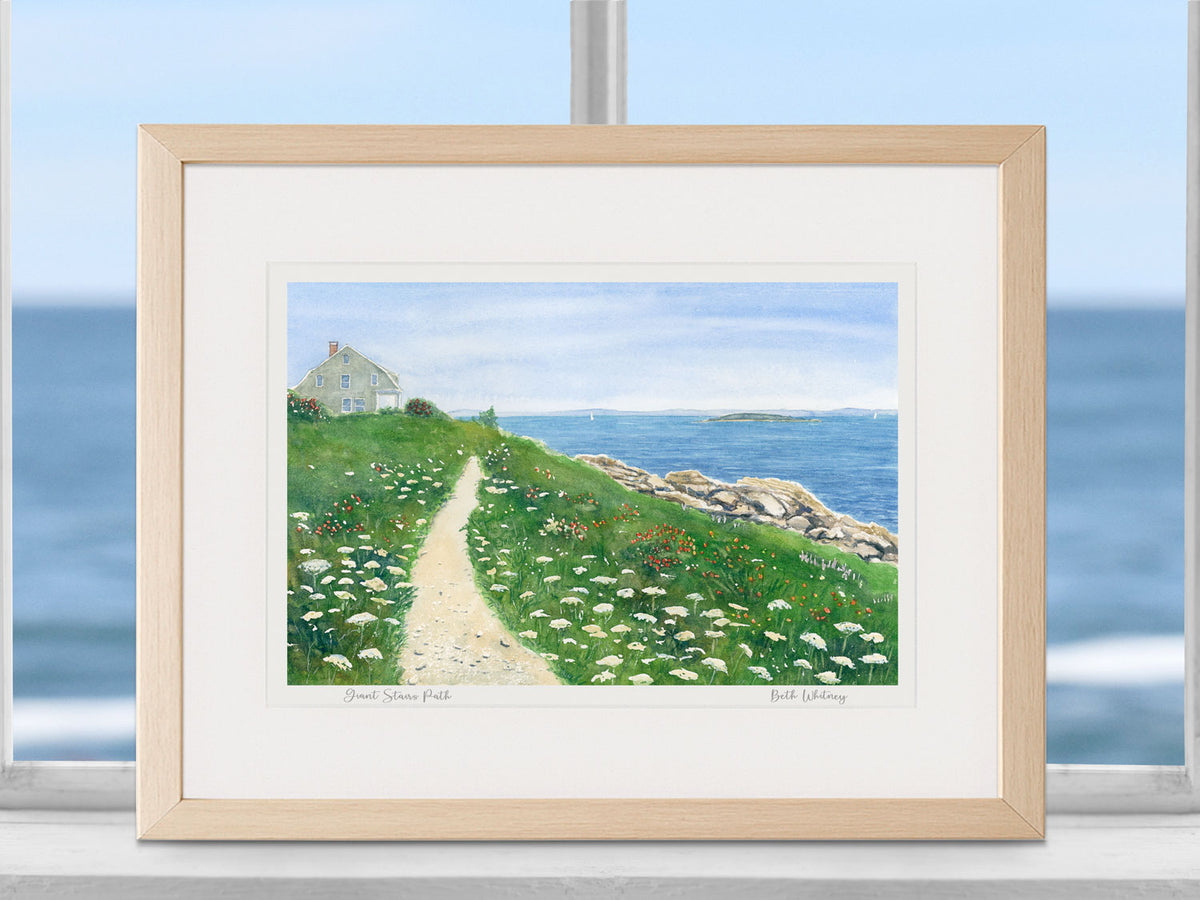 Framed watercolor print of Giant Stairs Path, Harpswell, Maine, in a warm wood frame in a coastal window setting.