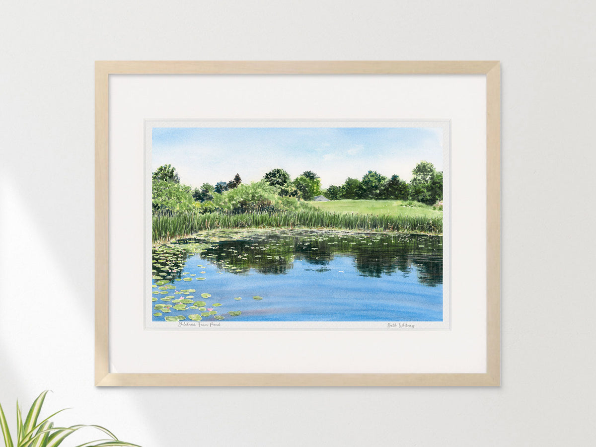 Framed watercolor print of Gilsland Farm Pond, Falmouth, Maine, in a warm wood frame on a neutral wall.
