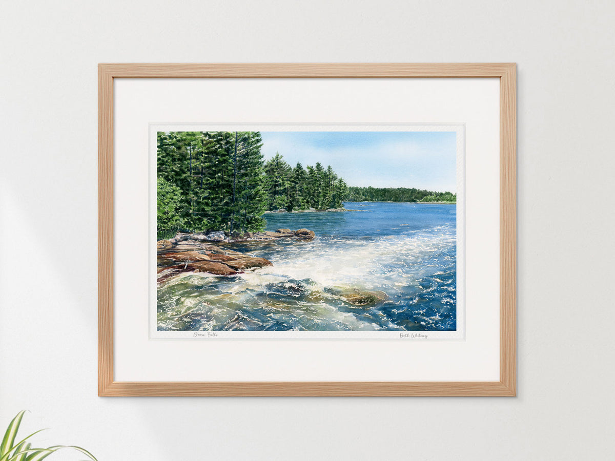 Framed watercolor print of Goose Falls, Harborside, Maine, in a warm wood frame on a neutral wall.
