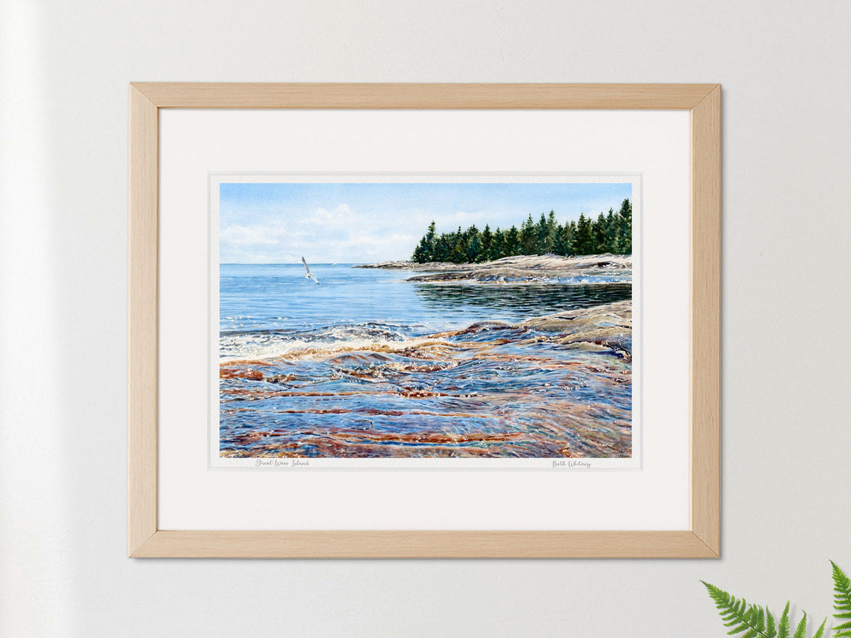 Framed watercolor print of Great Wass Island, Downeast Maine, in a warm wood frame on a neutral wall.