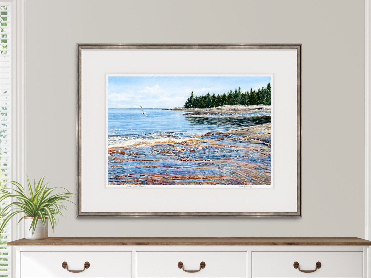 Framed watercolor print of Great Wass Island in a black frame above a dresser in a lifestyle setting.