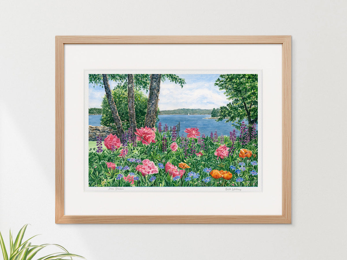 Framed watercolor print of June Garden, Friendship, Maine, in a warm wood frame on a neutral wall.