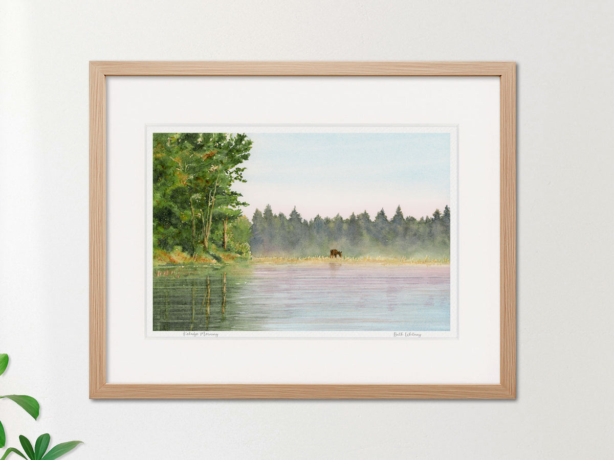 Framed watercolor print of Kokadjo Morning, Roach Pond, Maine, in a warm wood frame on a neutral wall.