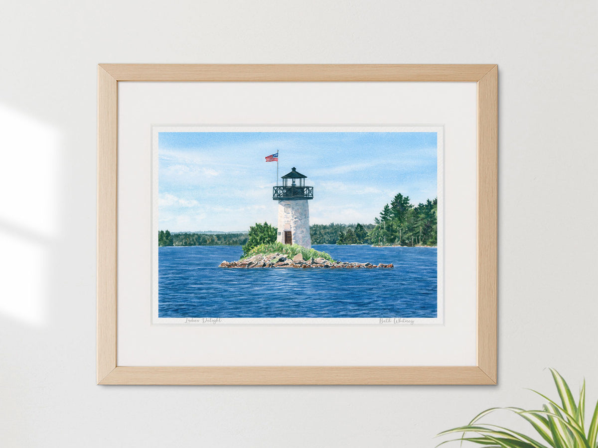 Framed watercolor print of Ladies Delight Light, Cobbosseecontee Lake, in a warm wood frame on a neutral wall.