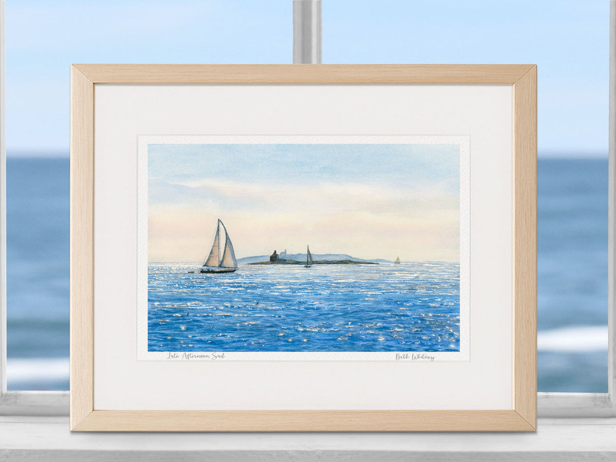 Framed watercolor print of Late Afternoon Sail in a warm wood frame in a coastal window setting.