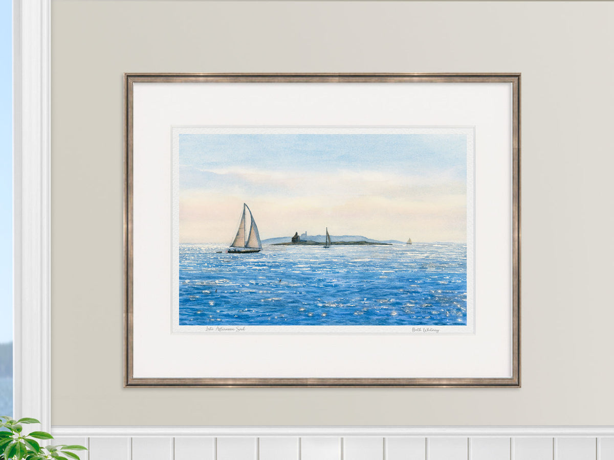 Framed watercolor print of Late Afternoon Sail, Boothbay Harbor, in a gold frame over white wainscotting.