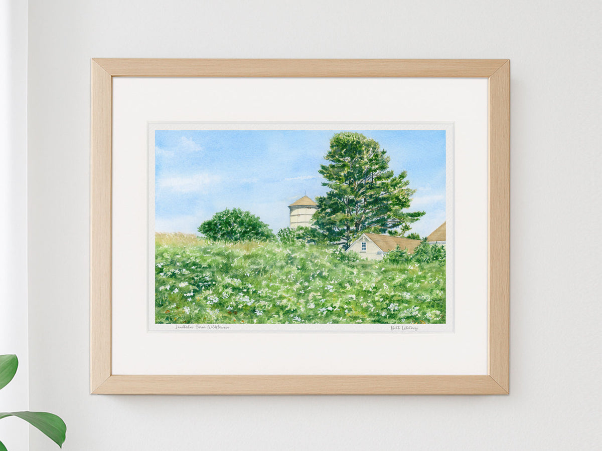 Framed watercolor print of Laudholm Farm Wildflowers, Wells, Maine, in a warm wood frame on a neutral wall.