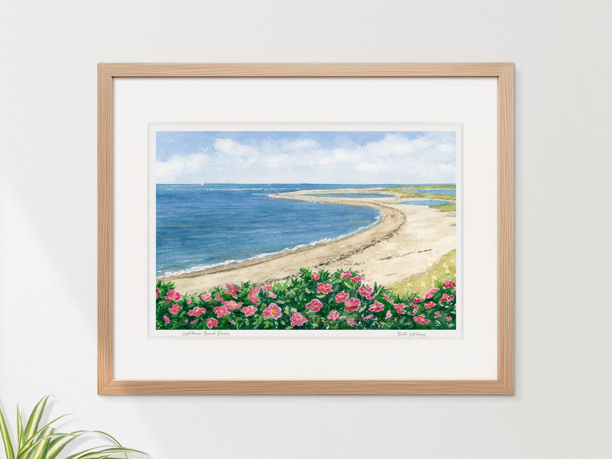 Framed watercolor print of Lighthouse Beach Roses, Chatham, Cape Cod, in a warm wood frame on a neutral wall.