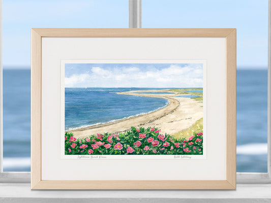 Framed watercolor print of Lighthouse Beach Roses, Cape Cod, in a warm wood frame in a coastal window setting.