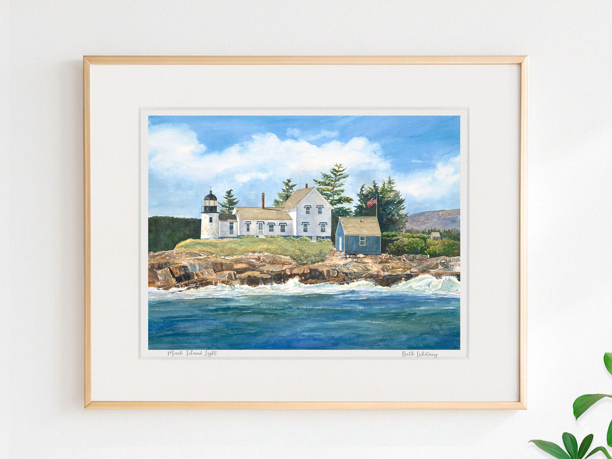 Framed watercolor print of Mark Island Light, Winter Harbor, Maine, in a warm wood frame on a neutral wall.