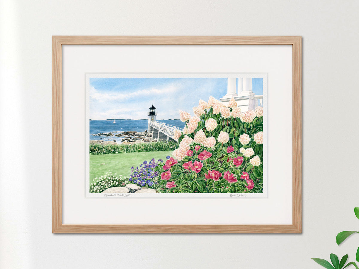 Framed watercolor print of Marshall Point Light, Port Clyde, Maine, in a warm wood frame on a neutral wall.