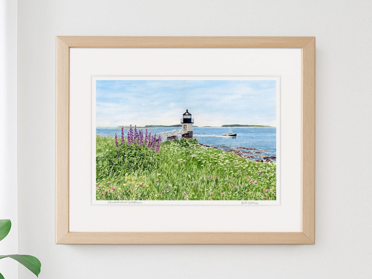 Framed watercolor print of Marshall Point Wildflowers, Port Clyde, Maine, in a warm wood frame on a neutral wall.