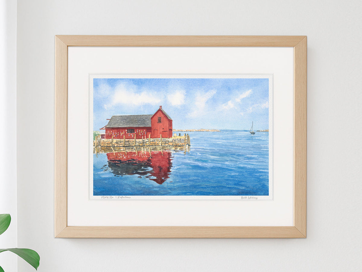 Framed watercolor print of Motif No. 1 Reflections, Rockport, Massachusetts, in a warm wood frame on a neutral wall with a plant.