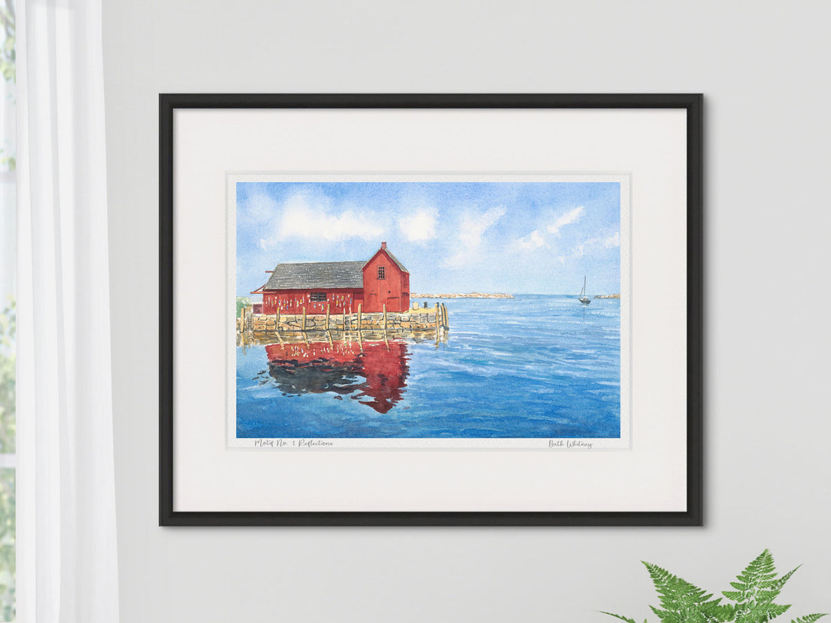 Framed watercolor print of Motif No. 1 Reflections, Cape Ann, Massachusetts, in a black frame beside a cozy window and fern.