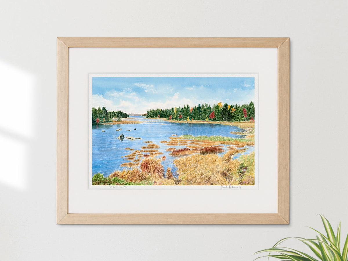 Framed watercolor print of Mt Desert Narrows, Mount Desert Island, Maine, in a warm wood frame on a sunny neutral wall with a plant.