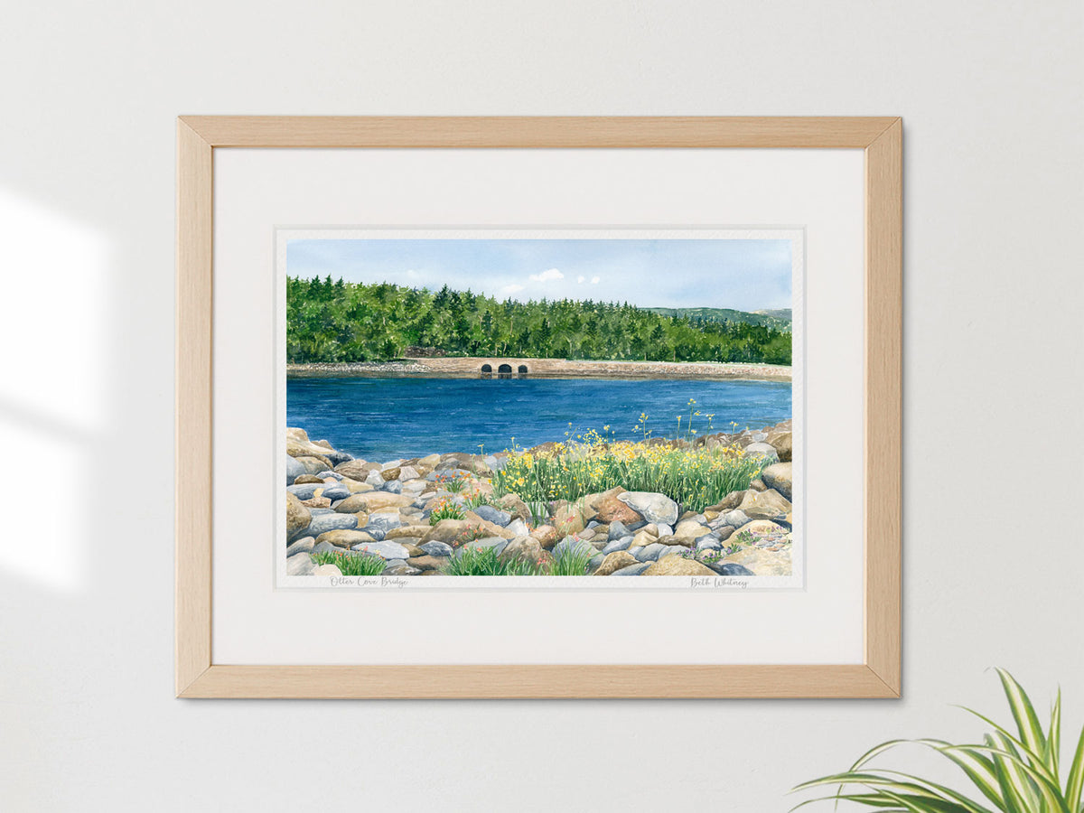 Framed watercolor print of Otter Cove Bridge, Acadia National Park, in a warm wood frame on a neutral wall.