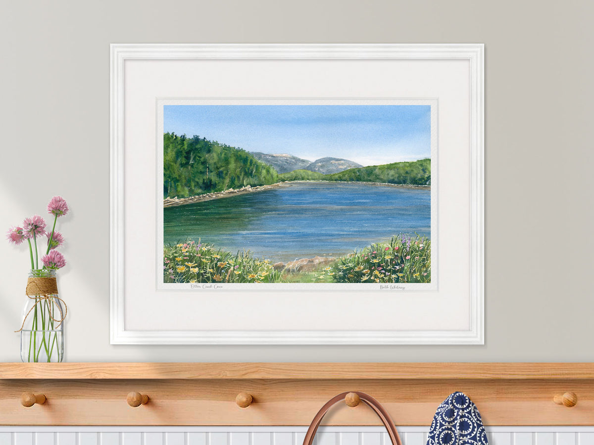 Framed watercolor print of Otter Creek Cove, Acadia National Park, in a white frame over a coastal inspired entryway decor.