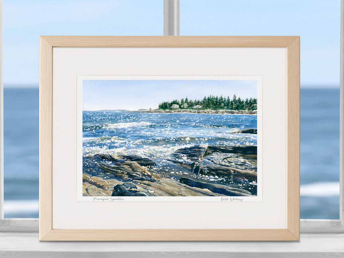 Framed watercolor print of Pemaquid Sparkles, Bristol, Maine, in a natural wood frame in a coastal window setting with an ocean view.
