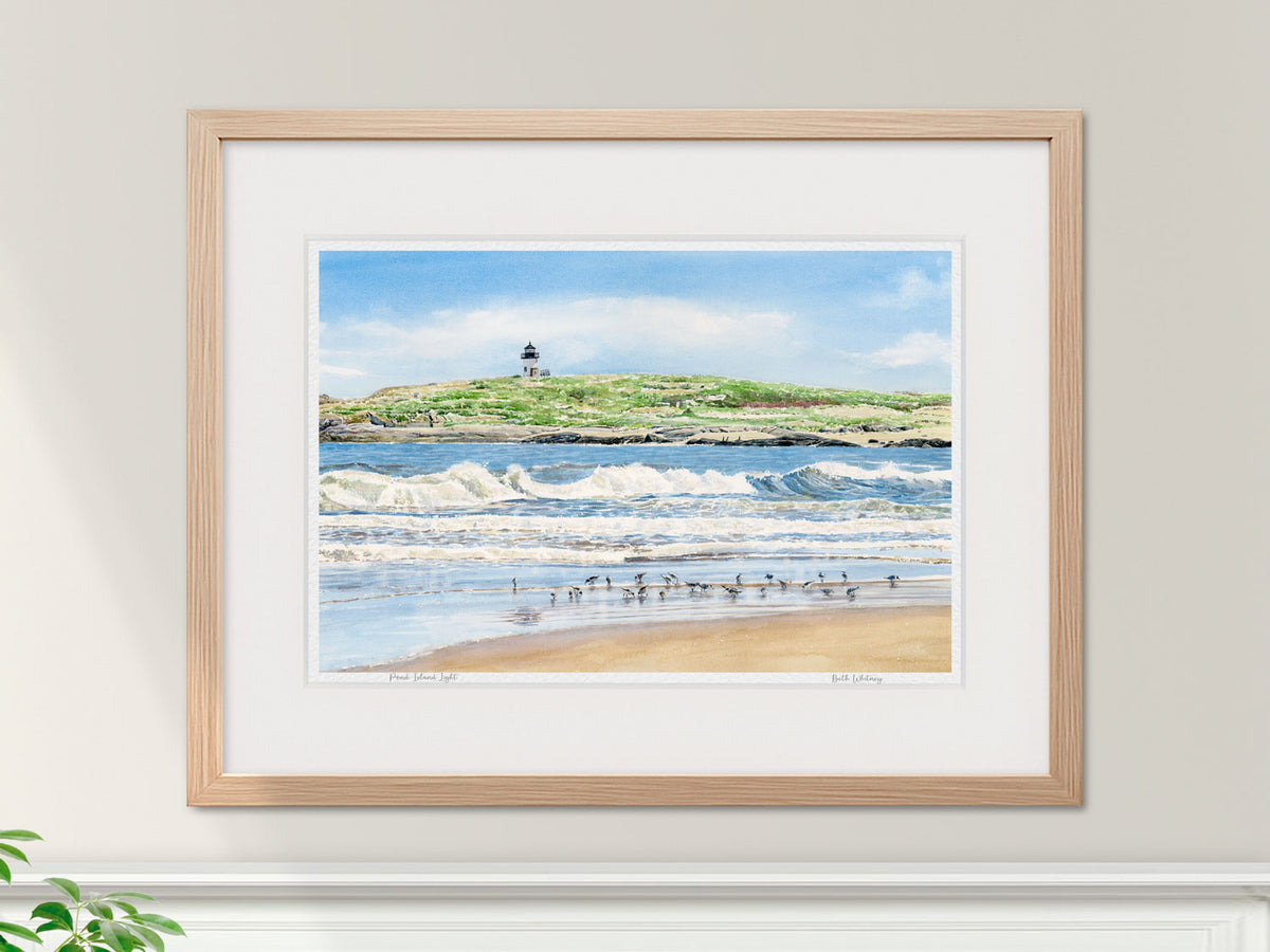 Framed watercolor print of Pond Island Light, Popham Beach, in a warm wood frame on a neutral wall.