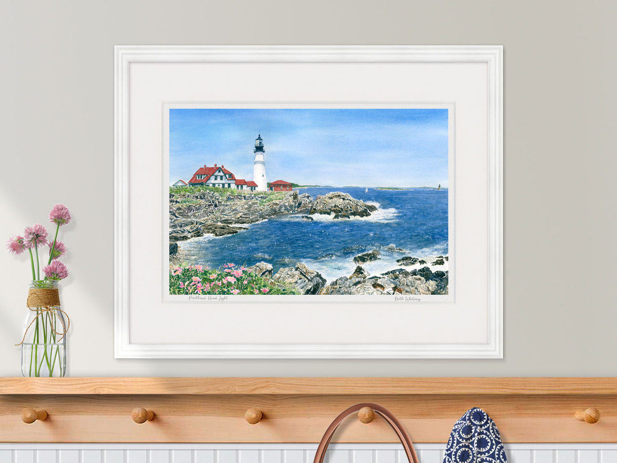 Framed watercolor print of Portland Head Light, Cape Elizabeth, in a white frame in a kitchen decor.