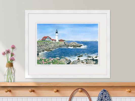 Framed watercolor print of Portland Head Light, Cape Elizabeth, in a white frame in a kitchen decor.