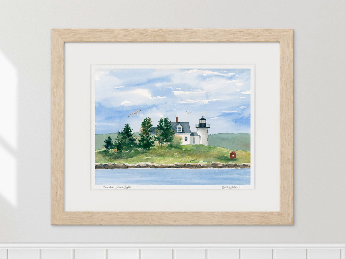 Framed watercolor print of Pumpkin Island Light, Little Deer Isle, in a warm wood frame on a neutral wall.
