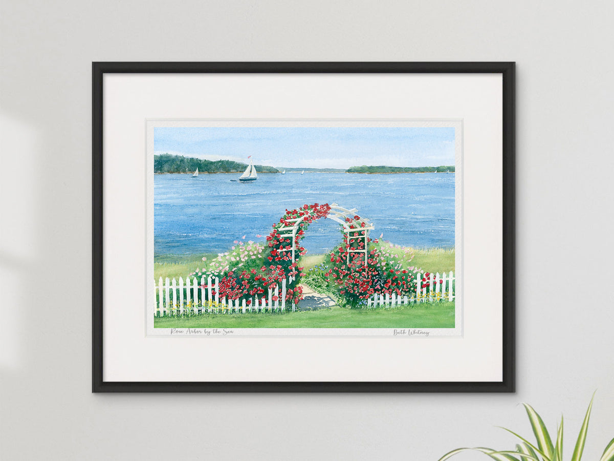 Framed watercolor print of Rose Arbor by the Sea, Penobscot Bay, Maine, in a contemporary black frame on a neutral wall.