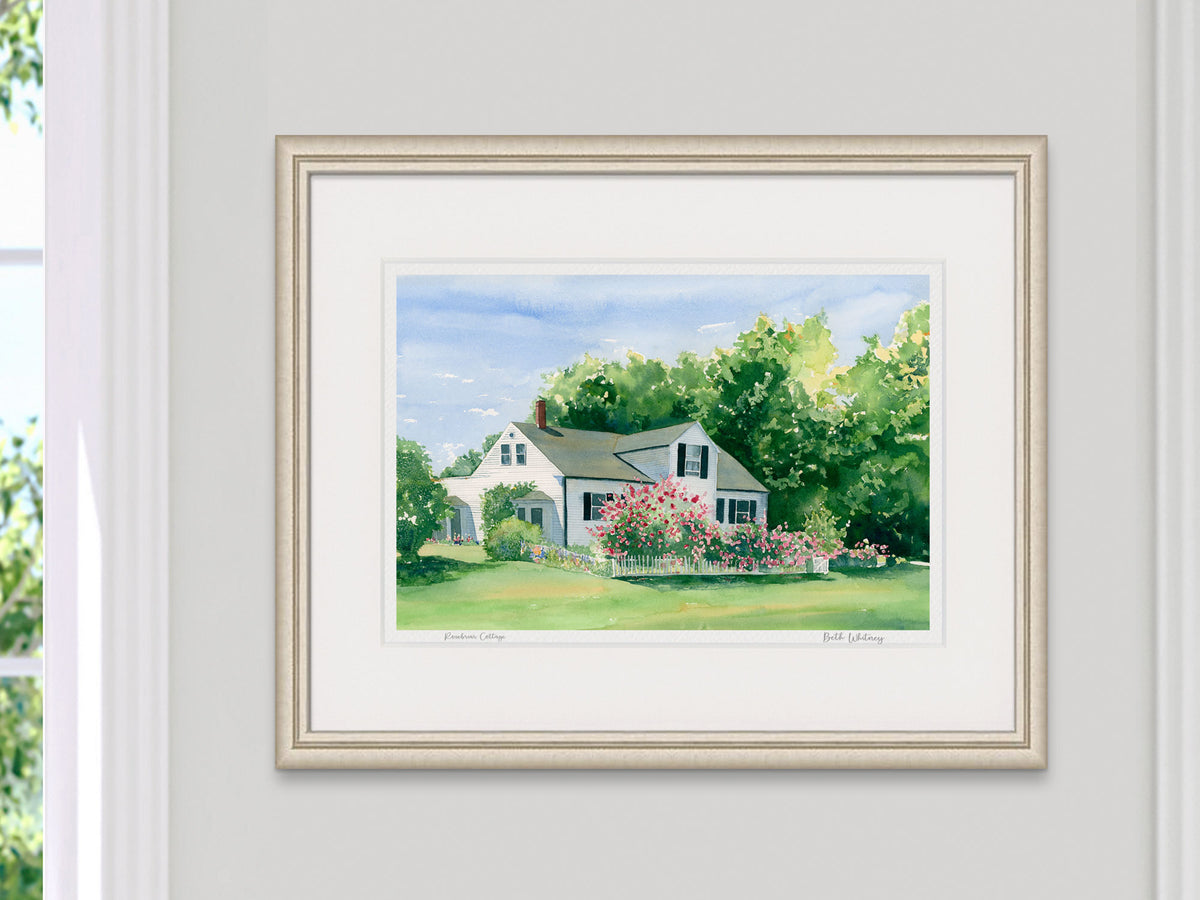 Framed watercolor print of Rosebriar Cottage, Blue Hill, Maine, displayed in a pale gold frame with soft natural window light.